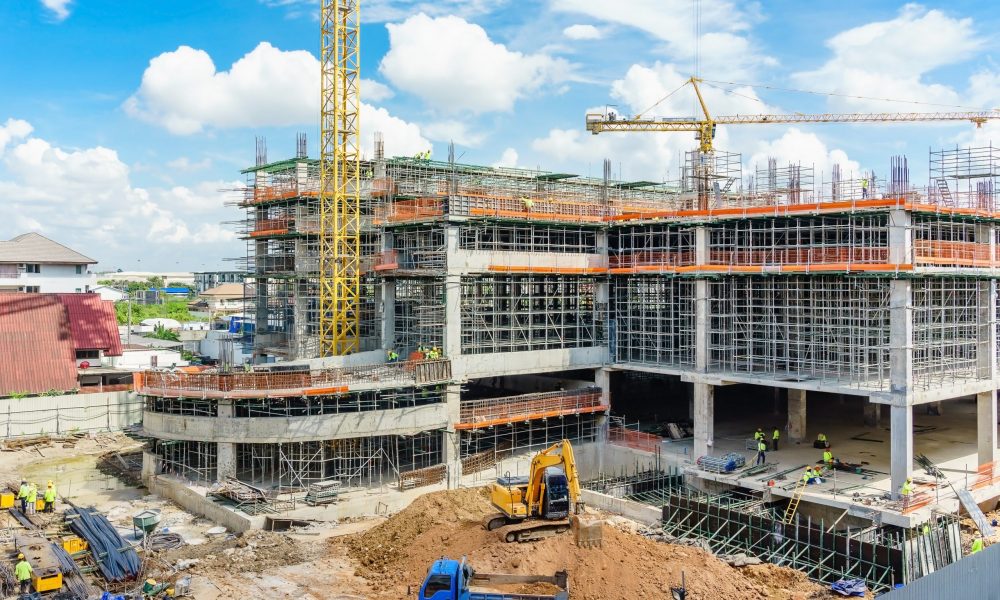 Construction site and unfinished high-rise building with scaffolding, Yellow tower crane and blue sky cloudy.